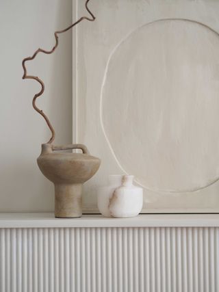 a ceramic vase in front of textured artwork