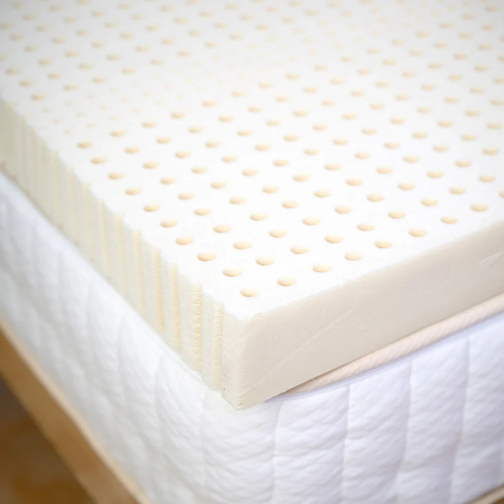Corner of the Turmerry Latex Mattress Topper on a bed.