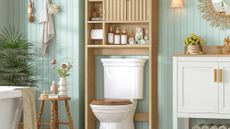 Wooden fluted over-toilet storage styled in a cheerful bathroom area with sea foam-slatted walls and assorted objects