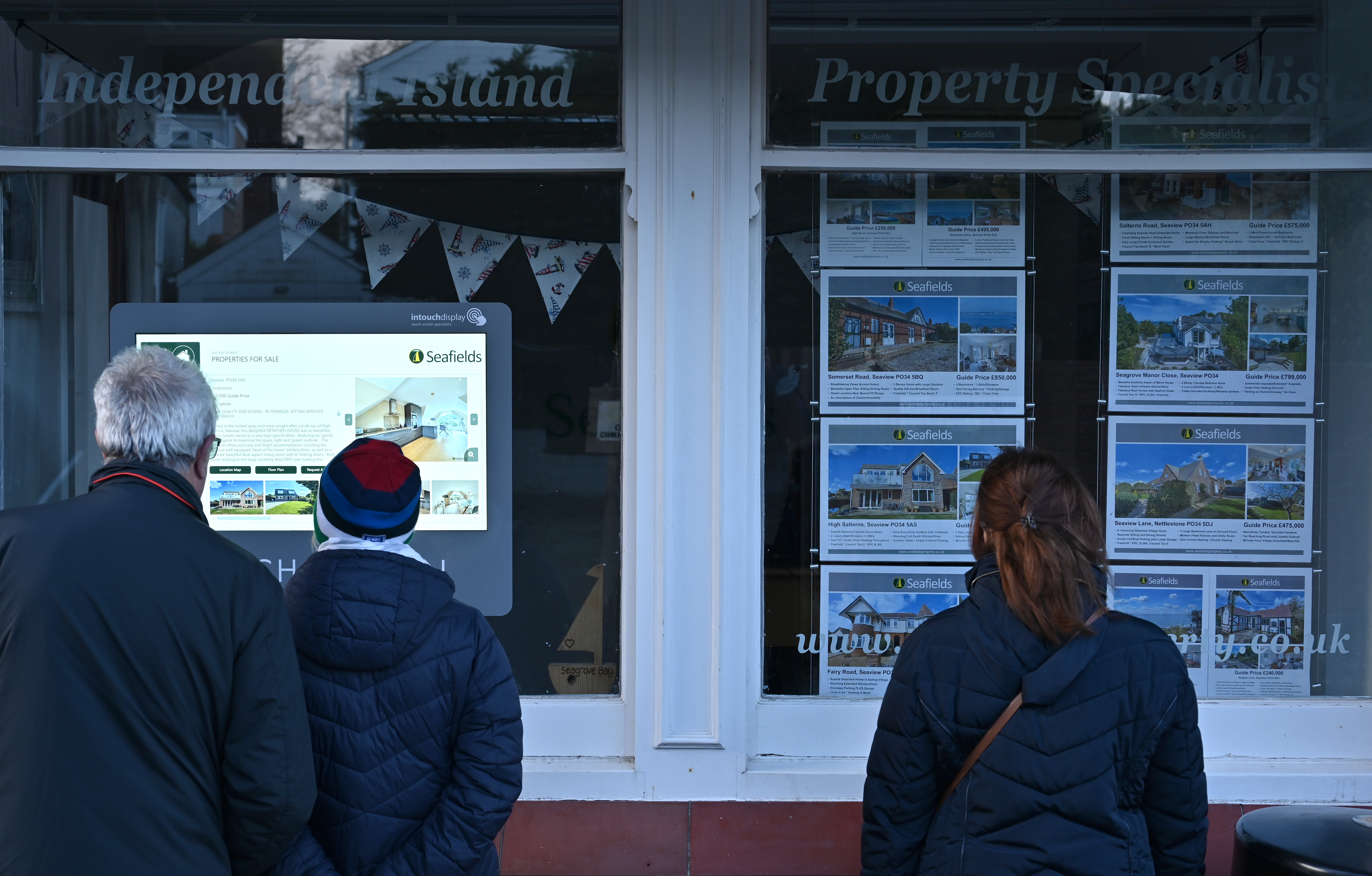 People looking through an estate agents window