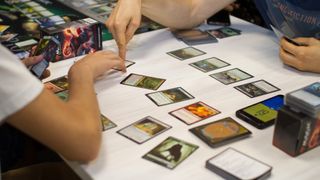Cards of board game Magic The Gathering are on the table while people play