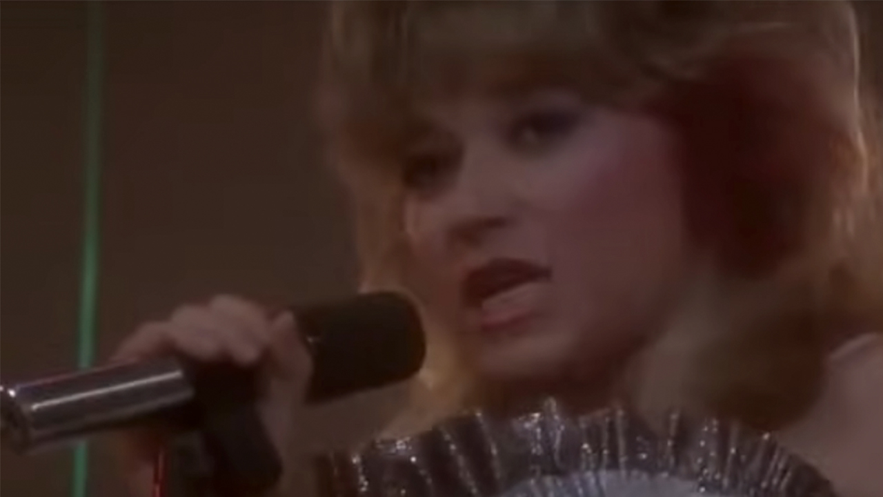 E. G. Daily singing into a microphone in Better Off Dead