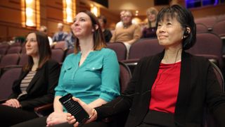 Two smiling women enjoy a theater production with the assistance of Williams AV.