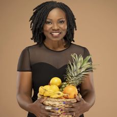 Headshot of Agatha Achindu, holding a basket of fresh fruit. 