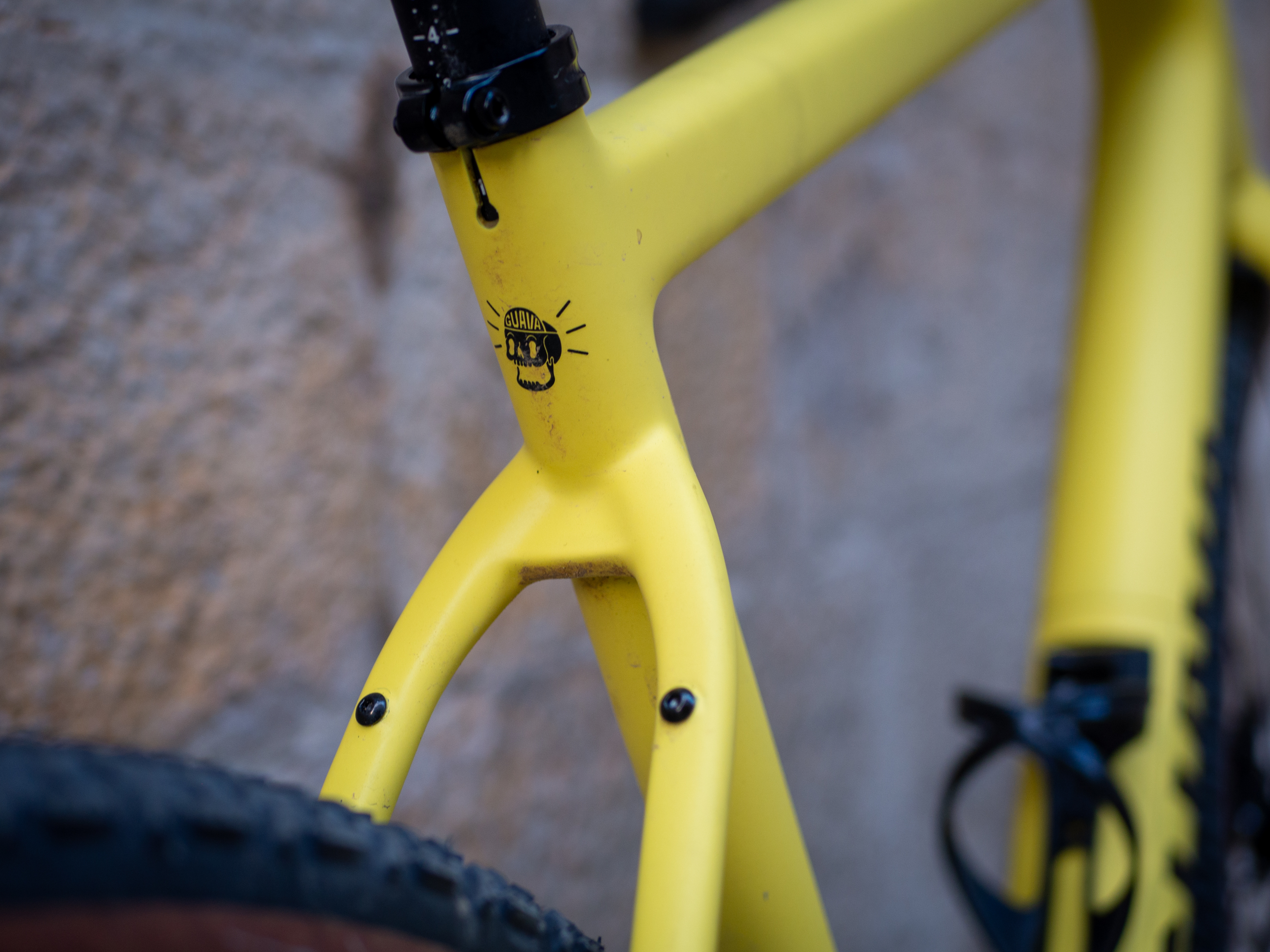 A yellow Guava Spot gravel bike leans against a wall