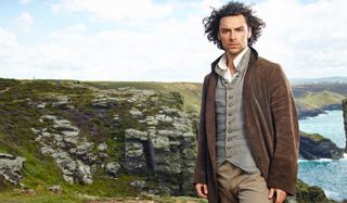 Poldark Aidan Turner stands on a windswept cliff