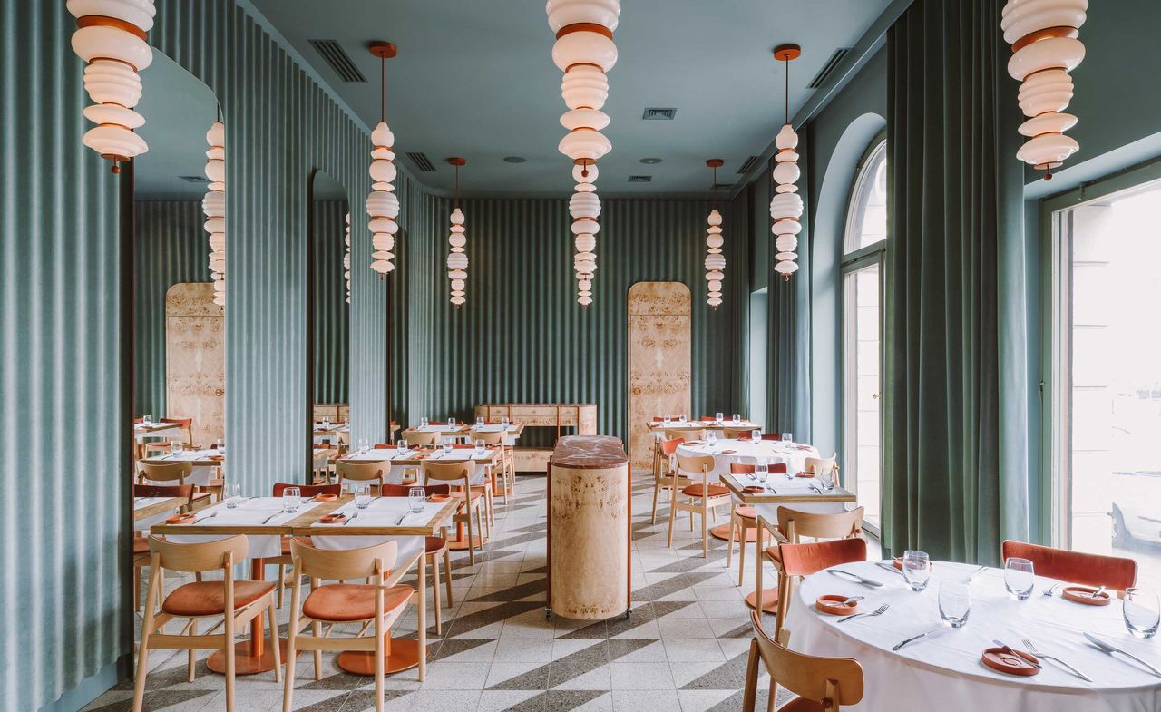 Interior of the Opasly Tom restaurant in Warsaw with green walls, tiled floors and terracotta coloured accents