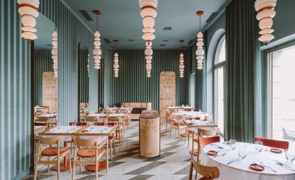 Interior of the Opasly Tom restaurant in Warsaw with green walls, tiled floors and terracotta coloured accents