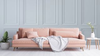living room with pale blue wall panelling and pink sofa