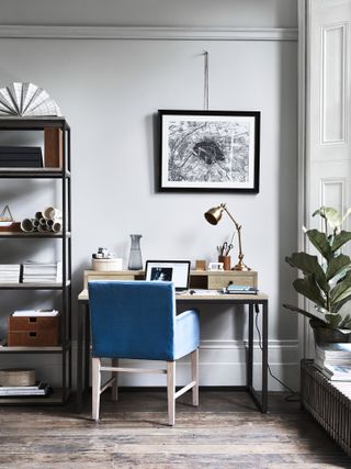 Neptune wooden Carter desk, Brompton desk lamp in Antique Brass , and a city plan print on the wall, and wooden floor and gray walls