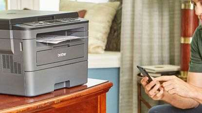 Best wireless printer - Brother HL-L2390DW being used by man with phone