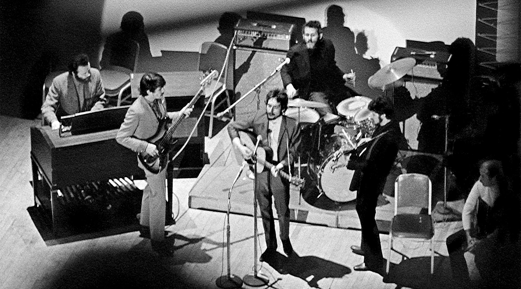At Carnegie Hall, Bob Dylan performed with The Band, as part of a memorial concert "Tribute to Woody Guthrie." This was Dylan's first public appearance after 18 months of self-imposed seclusion. L-R: Garth Hudson, Rick Danko, Dylan, Levon Helm, Robbie Robertson. At right listening is folksinger Tom Paxton.