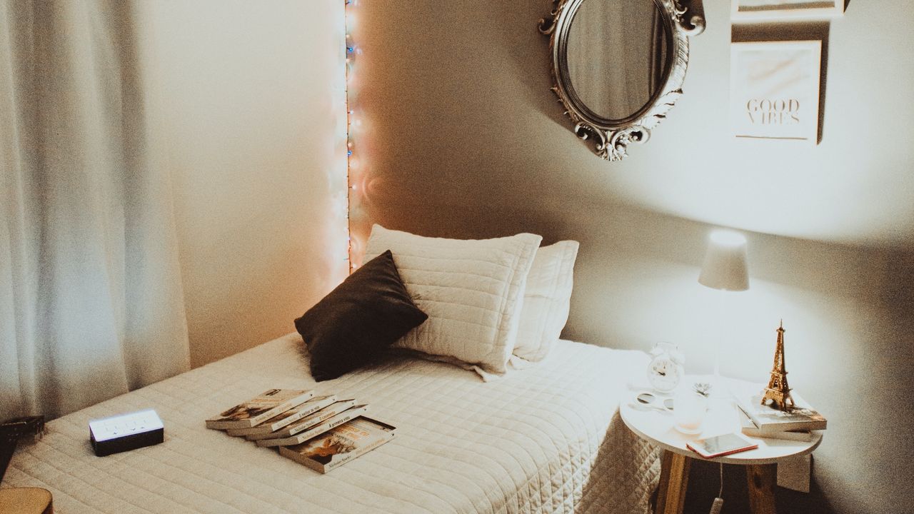 A bedroom with lights and made up bed