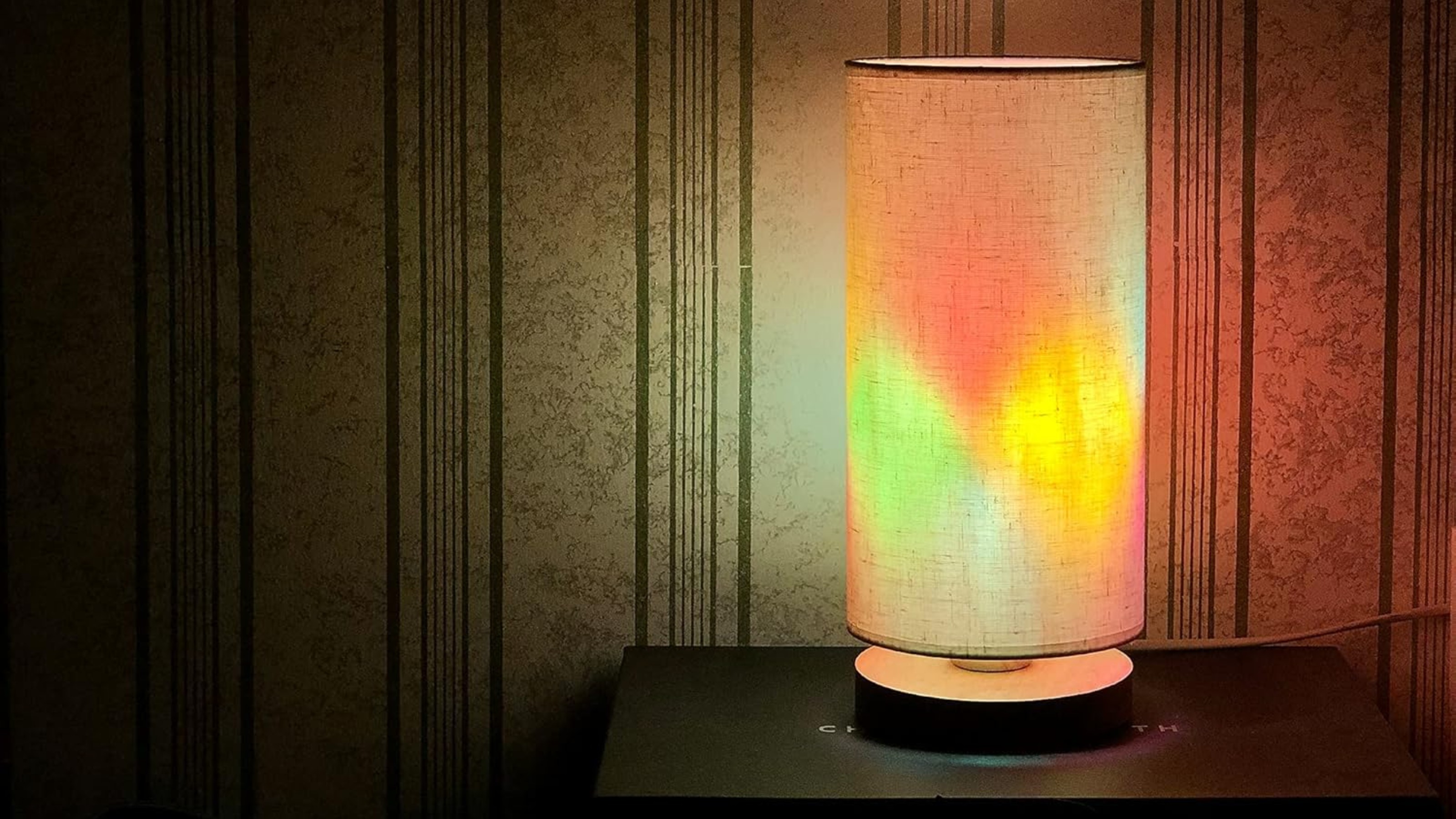 A switched on table lamp with a stained glass light bulb in a dark room