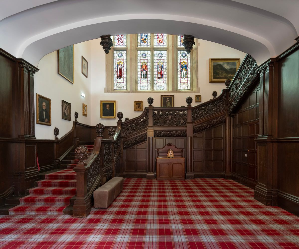 A wooden staircase with chequered carpet