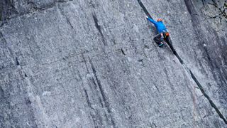 Man climbing up steep rock face at Slate quarry in North Wales