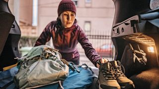 Woman packing her car with hiking equipment and preparing for new adventure