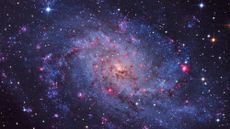 A image of a swirling galaxy and stars with pinks, blues and brooding colors