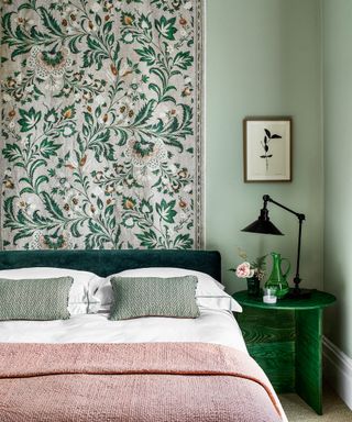 A sage green bedroom with a hanging botanical tapestry