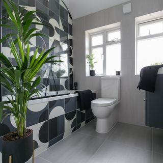 bathroom with grey floor tiles and graphic monochrome wall and bath tiles