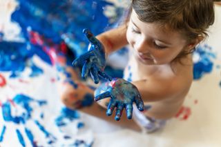 A close up of a toddler doing hand paint prints