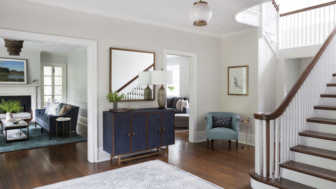 A view of a foyer with blue sideboard, and views into the dining room, living room and den