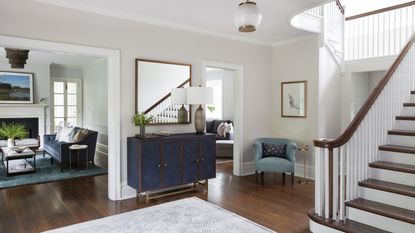 A view of a foyer with blue sideboard, and views into the dining room, living room and den