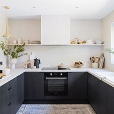 Dark grey u-shaped kitchen with work worktops and a single open shelf running across the back wall