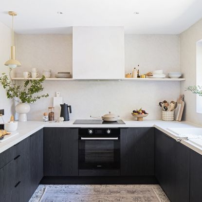 Dark grey u-shaped kitchen with work worktops and a single open shelf running across the back wall