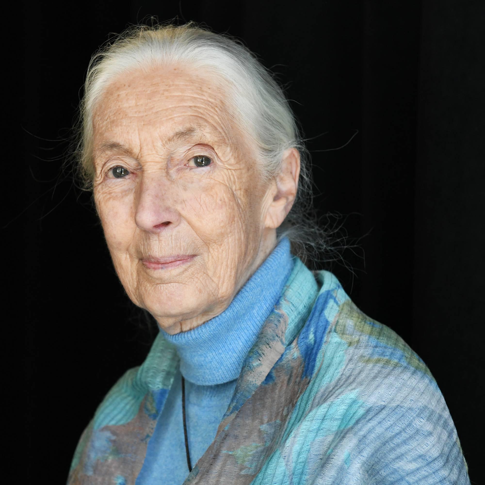 Jane Goodall smiles into the camera in front of a black background