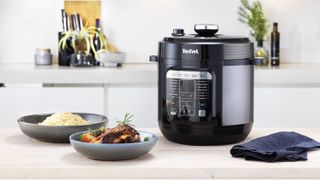 Tefal 6L Home Chef Smart Multicooker on a kitchen island with plates of food