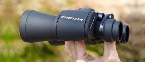 Celestron Cometron 7x50 binoculars in hands with foliage as a backdrop