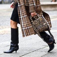 FRANKFURT AM MAIN, GERMANY - JANUARY 18: A leopard print bag by Dior and black knee high boots by Patrizia Pepe as a detail of influencer Simone Adams, seen during the Frankfurt Fashion Week January 2022 on January 18, 2022 in Frankfurt am Main, Germany. (Photo by Streetstyleshooters/Getty Images)