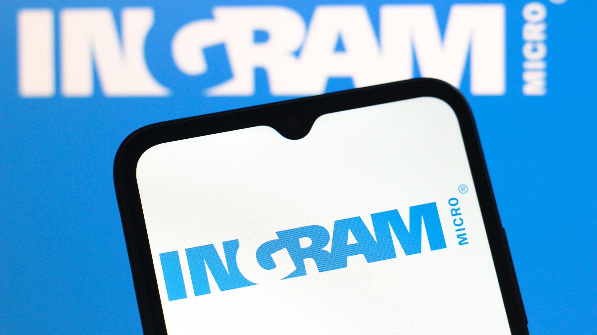 Ingram Micro logo and branding pictured on a smartphone screen with logo and branding also visible in background.