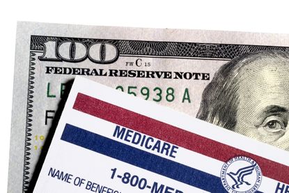 Close up of a Medicare card on top of a $100 bill. 