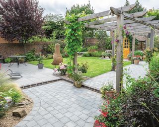 brick paved L shape patio with a rustic timber pergola