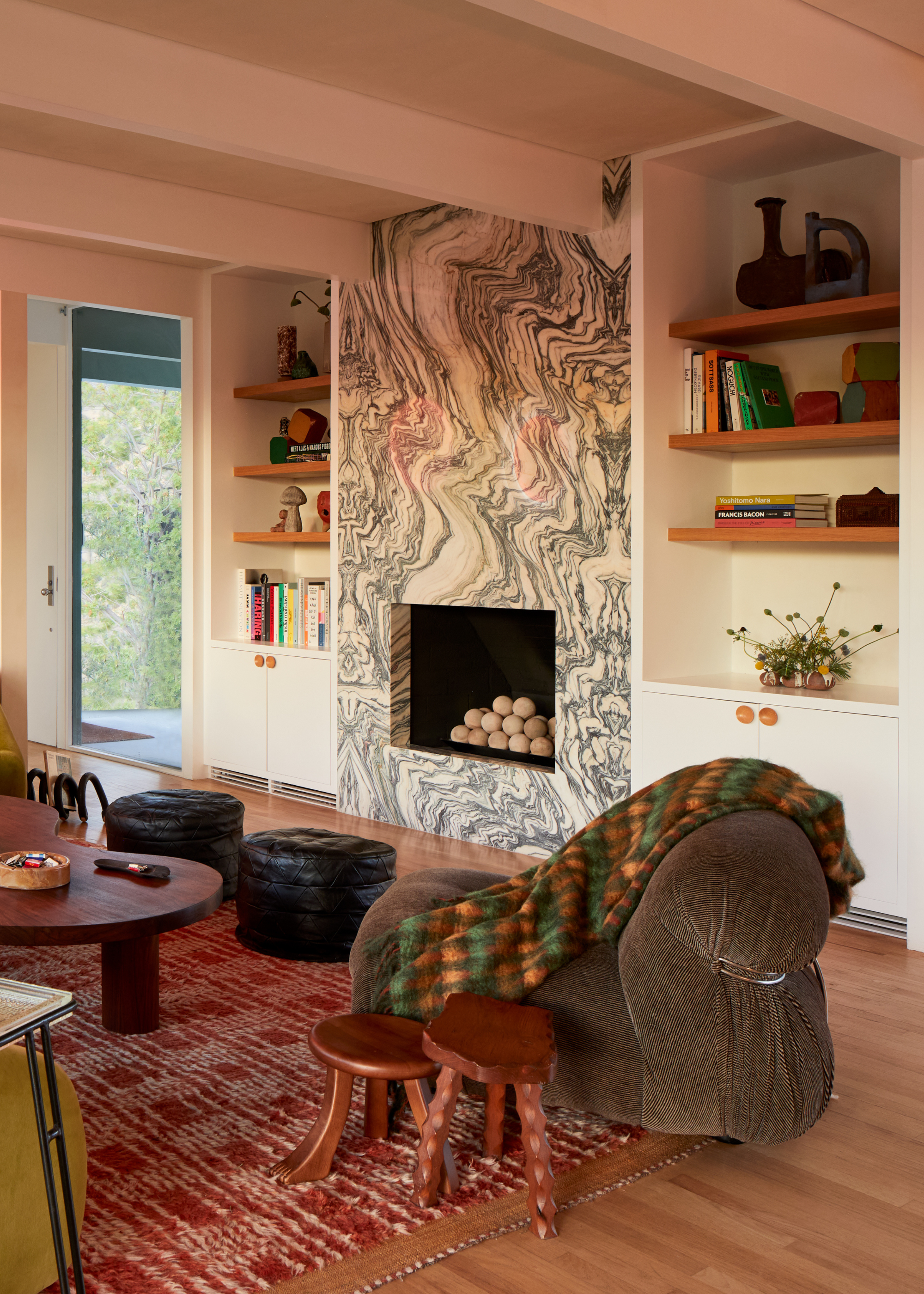 A living room with a marble fireplace between floating wood book shelves