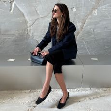 Eliza Huber wearing a navy blue blazer, capri pants, and pointed-toe flats.