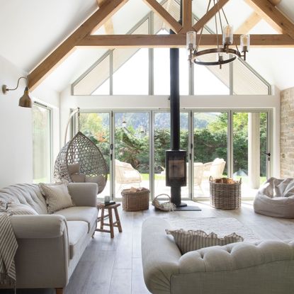 living area with neutral sofas, woodburner and wooden beams