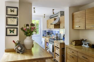 galley kitchen with wooden freestanding units and blue tiles