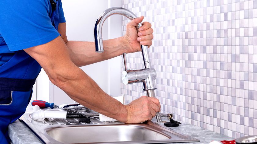 Person fitting chrome kitchen mixer tap into metal sink