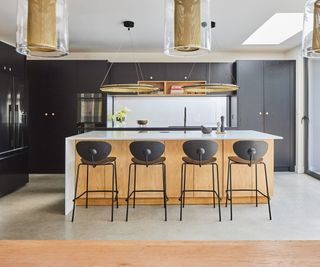 A kitchen in a newly refurbished home. The cabinets are floor to ceiling and a matte black cabinet. There is pendant lighting above the kitchen island