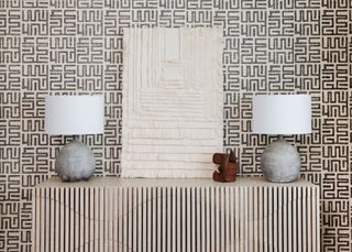 a console table with symmetrical lamps and artwork