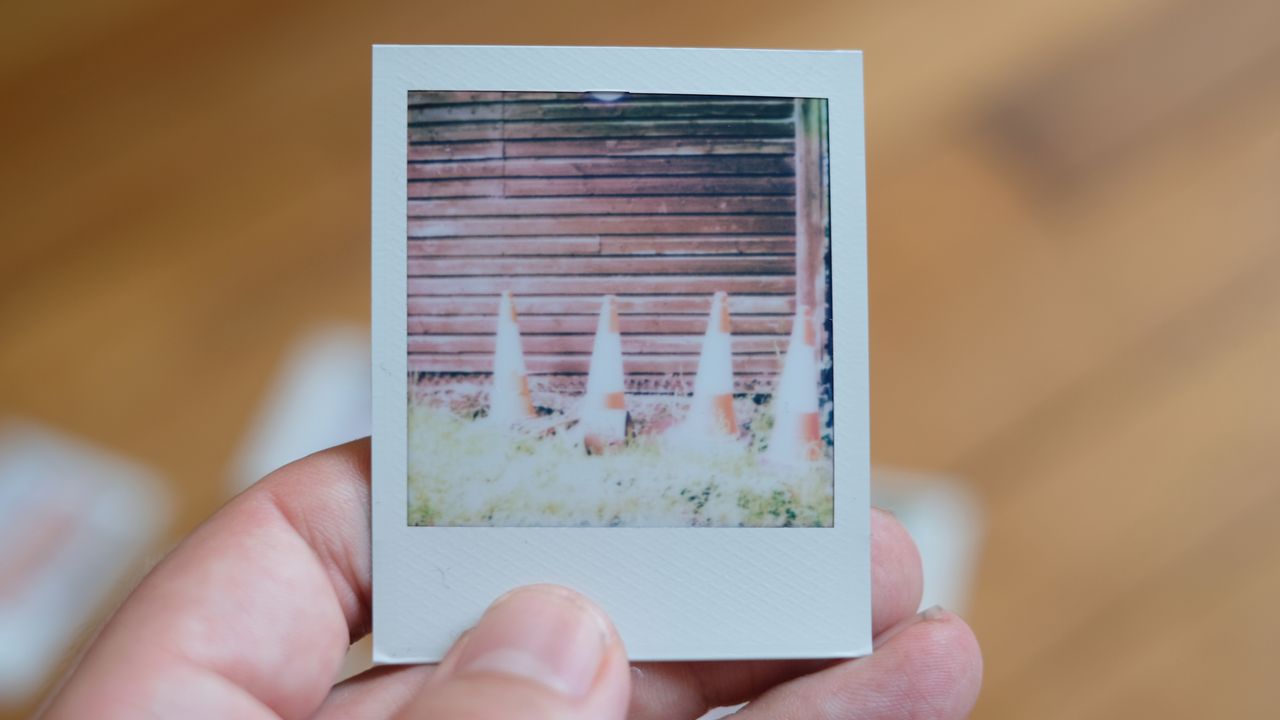 Photograph of prints made with Polaroid Go Gen 3 showing four traffic cones, overexposed