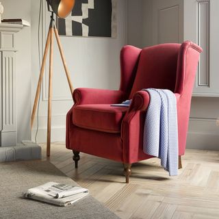 A red armchair with a blue blanket in neutral living room