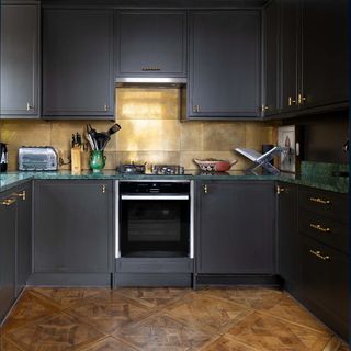 Kitchen with charcoal kitchen cabinets and metallic tile splashback