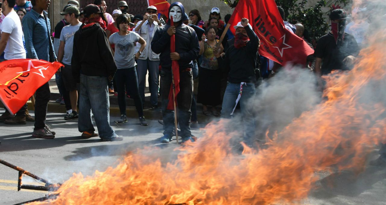 Demonstrators set on fire campaign posters of Juan Orlando Hernandez in front of the US embassy