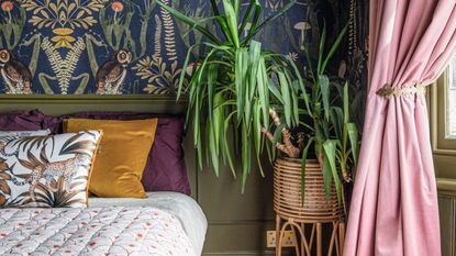 Bedroom with wallpaper accent wall and wall panelling, jewel toned bedding and houseplant