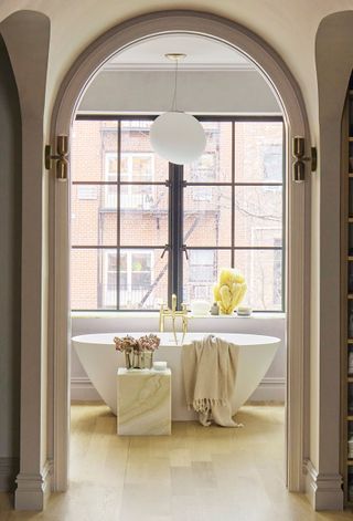 a light and airy bathroom with a freestanding bath and a marble side table