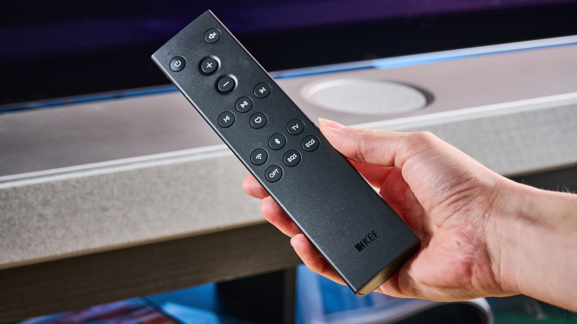 the KEF XIO soundbar in gray photographed with a TV and the Tom's Guide blue background